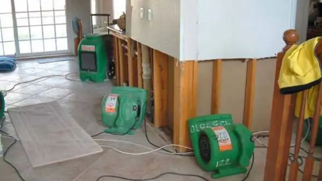 Air movers running beside an opened wall cavity after water damage